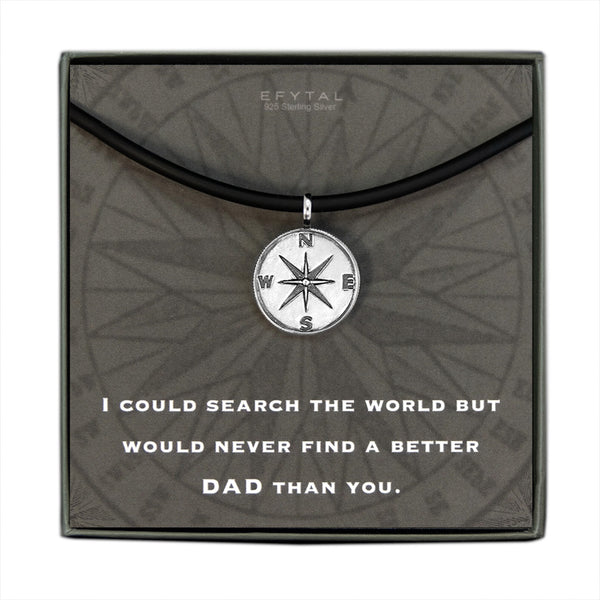 A grey jewelry box containing a grey message card with tonal compass motif. A black silicone cord with a Sterling Silver compass pendant rests on the card. The white text on the card reads “EFYTAL 925 Sterling Silver” at the top and “I COULD SEARCH THE WORLD BUT WOULD NEVER FIND A BETTER DAD THAN YOU.”  