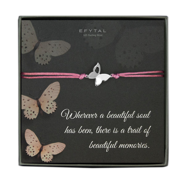 A grey jewelry box containing a grey message card with a blush butterfly motif. A pink cord bracelet with a sterling silver butterfly charm rests on the card. The white text on the card reads “EFYTAL 925 Sterling Silver” at the top and “Wherever a beautiful soul has been, there is a trail of beautiful memories.” at the bottom. 