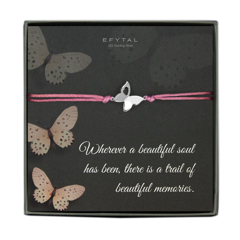 A grey jewelry box containing a grey message card with a blush butterfly motif. A pink cord bracelet with a sterling silver butterfly charm rests on the card. The white text on the card reads “EFYTAL 925 Sterling Silver” at the top and “Wherever a beautiful soul has been, there is a trail of beautiful memories.” at the bottom. 