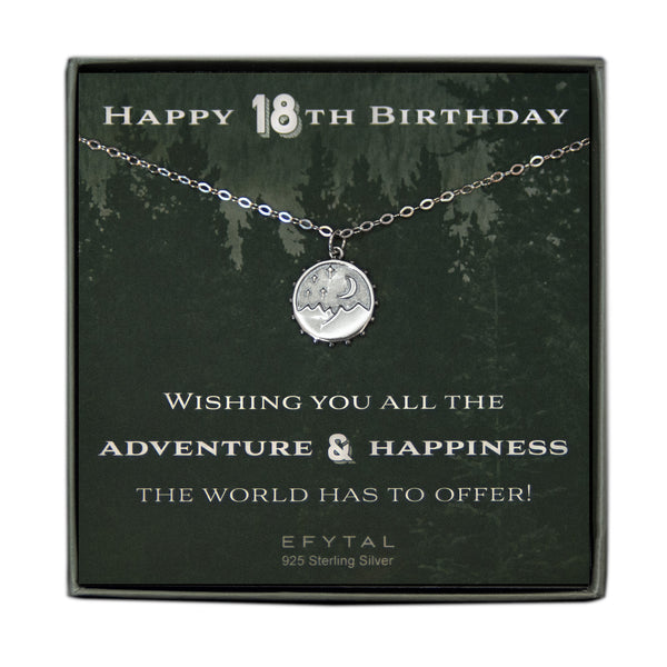 A grey jewelry box containing a green message card with a tonal forest motif. A 925 Sterling Silver necklace with a 925 sterling silver round pendant with mountain, moon and stars motif rests on the card. The white text on the card reads “HAPPY 18TH BIRTHDAY” at the top and “WISHING YOU ALL THE ADVENTURE & HAPPINESS THE WORLD HAS TO OFFER! EFYTAL 925 Sterling Silver” at the bottom.  