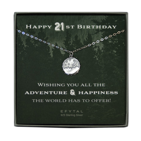 A grey jewelry box containing a green message card with a tonal forest motif. A 925 Sterling Silver necklace with a 925 sterling silver round pendant with mountain, moon and stars motif rests on the card. The white text on the card reads “HAPPY 21ST BIRTHDAY” at the top and “WISHING YOU ALL THE ADVENTURE & HAPPINESS THE WORLD HAS TO OFFER! EFYTAL 925 Sterling Silver” at the bottom.  