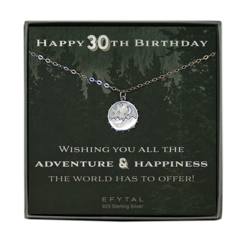A grey jewelry box containing a green message card with a tonal forest motif. A 925 Sterling Silver necklace with a 925 sterling silver round pendant with mountain, moon and stars motif rests on the card. The white text on the card reads “HAPPY 30TH BIRTHDAY” at the top and “WISHING YOU ALL THE ADVENTURE & HAPPINESS THE WORLD HAS TO OFFER! EFYTAL 925 Sterling Silver” at the bottom.  