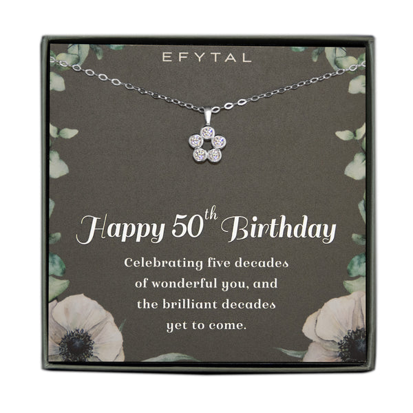 Grey jewelry box containing a silver necklace with a cluster of 5 cz stones, placed on a grey card with a border of green leaves and two anemone flowers in the bottom corners. The text on the card reads "EFYTAL" at the top and "Happy 50th Birthday. Celebrating five decades of wonderful you and the brilliant decades yet to come" on the bottom.