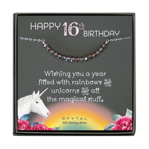 grey jewelry box containing silver necklace with sixteen iridescent purple glass beads, placed on a grey card. The bottom left corner of the card has a unicorn and roses, there is a rainbow in the bottom center, and a rose on the bottom right corner. The card reads "Happy 16th birthday" in pink and white font at the top, and "Wishing you a year filled with rainbows and unicorns and all the magical stuff <3" underneath in white. "EFYTAL 925 sterling silver" is in small dark text at the bottom of the card. 