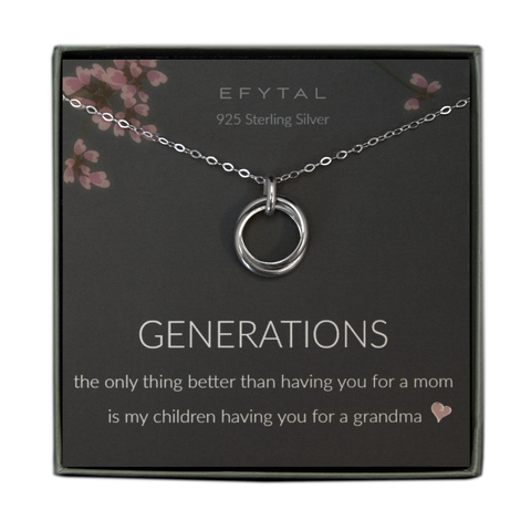 A grey jewelry box contains a grey message card with pink floral branch motifs on the top. A sterling silver necklace with a pendant of two thick rings rests on the card. The white text on the card reads "EFYTAL 925 Sterling Silver" at the top and "GENERATIONS the only thing better than having you for a mom is my children having you for a grandma <3"