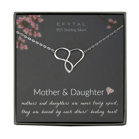 A grey jewelry box contains a grey message card with pink branch motif at the top. A sterling silver necklace with a half-heart, half-infinity sign pendant rests on the card. The white text at the top of the card reads "EFYTAL 925 Sterling Silver" and "Mother & Daughter <3 mothers and daughters are never truly apart, they are bound by each others' beating heart"