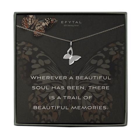 A grey jewelry box contains a grey message card with a large butterfly motif in the middle and a smaller butterfly on the top left. A silver necklace with a butterfly pendant featuring a heart shaped cutout in one wing rests across the card. In white text, the card reads "EFYTAL 925 Sterling Silver" at the top and "WHEREVER A BEAUTIFUL SOUL HAS BEEN, THERE IS A TRAIL OF BEAUTIFUL MEMORIES" at the bottom.