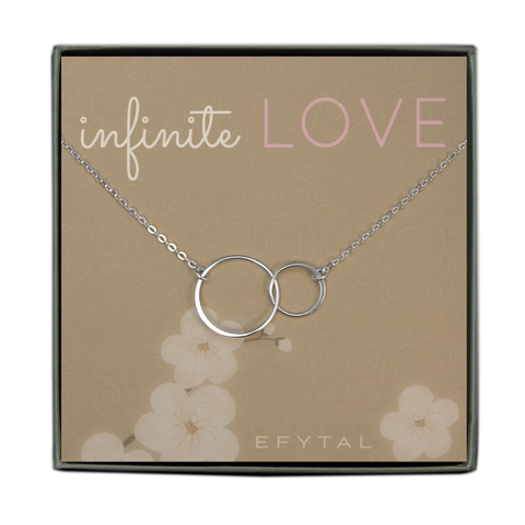 A grey jewelry box contains a beige message card with white swirl and flower motifs. A sterling silver necklace with two interlocking thin rings rests on the card. The text at the top of the card reads "infinite LOVE" in white and pink. The text in the bottom corner of the card reads "EFYTAL"