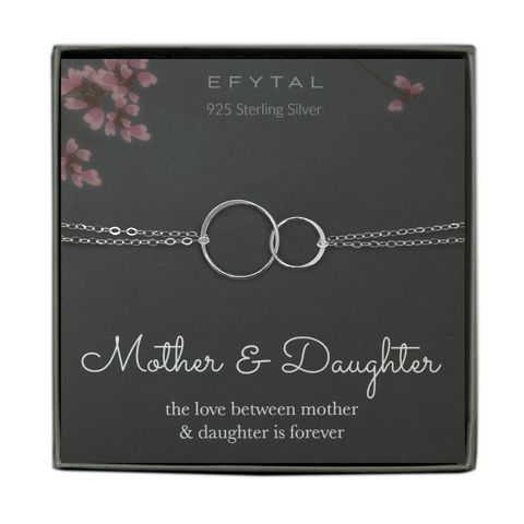 A grey jewelry box holds a grey message card with pink flower motif at the top. A sterling silver bracelet with two joined rings rests on the card. The text above the necklace reads "EFYTAL 925 Sterling Silver" in cream text. Underneath the necklace, the text reads "Mother & Daughter the love between mother & daughter is forever"