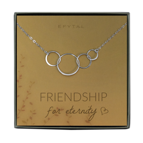A green jewelry box holds a yellow jewelry card with brown leaf motif in the bottom left corner. A sterling silver necklace with four interlocked silver rings rests on the card. The text above the jewelry reads "EFYTAL" in brown font, and below the necklace the card says "FRIENDSHIP for eternity <3"