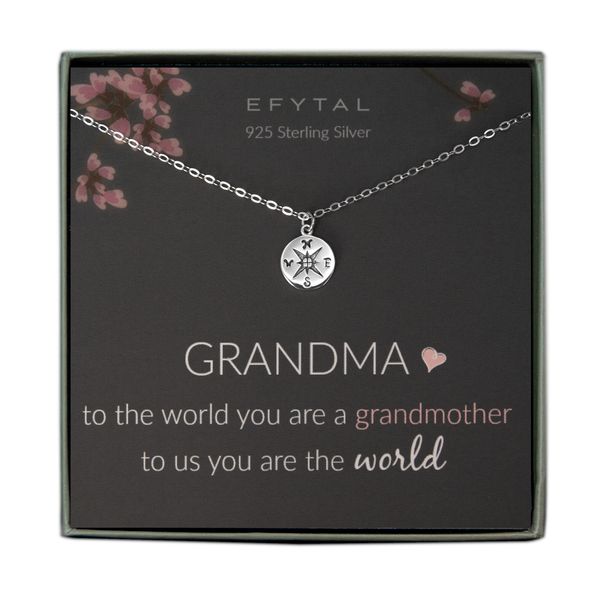 A grey jewelry box containing a grey message card with pink floral motif at the top. A silver necklace with a sterling silver necklace with a small compass pendant rests on the card. The white text on the card reads "EFYTAL 925 Sterling Silver" at the top and “GRANDMA <3 to the world you are a grandmother to us you are the world” at the bottom.