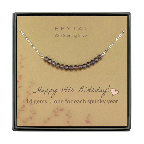  grey jewelry box containing silver necklace with fourteen iridescent purple glass beads, placed on a faded yellow card with a branch motif in the lower left corner. the text on the card reads "EFYTAL 925 sterling silver" in brown at the top and "Happy 14th Birthday! 14 gems...one for each spunky year" at the bottom.