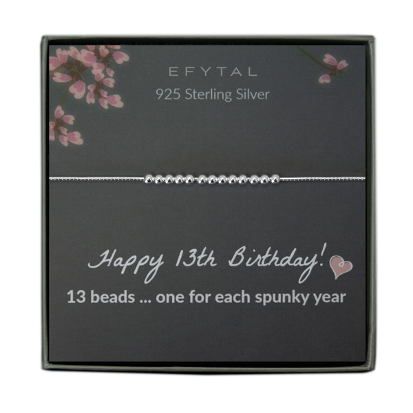  grey jewelry box containing a silver bracelet with thirteen round silver beads, placed on a grey card with pink flowers at the top. the text on the card reads "EFYTAL 925 sterling silver" at the top and "Happy 13th Birthday! <3 13 beads... one for each spunky year" at the bottom.