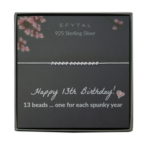  grey jewelry box containing a silver bracelet with thirteen round silver beads, placed on a grey card with pink flowers at the top. the text on the card reads "EFYTAL 925 sterling silver" at the top and "Happy 13th Birthday! <3 13 beads... one for each spunky year" at the bottom.
