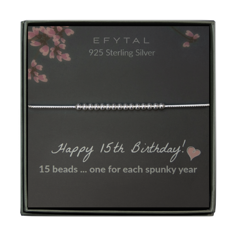 grey jewelry box containing a silver bracelet with fifteen round silver beads, placed on a grey card with pink flowers at the top. the text on the card reads "EFYTAL 925 sterling silver" at the top and "Happy 15th Birthday! <3 15 beads... one for each spunky year" at the bottom.