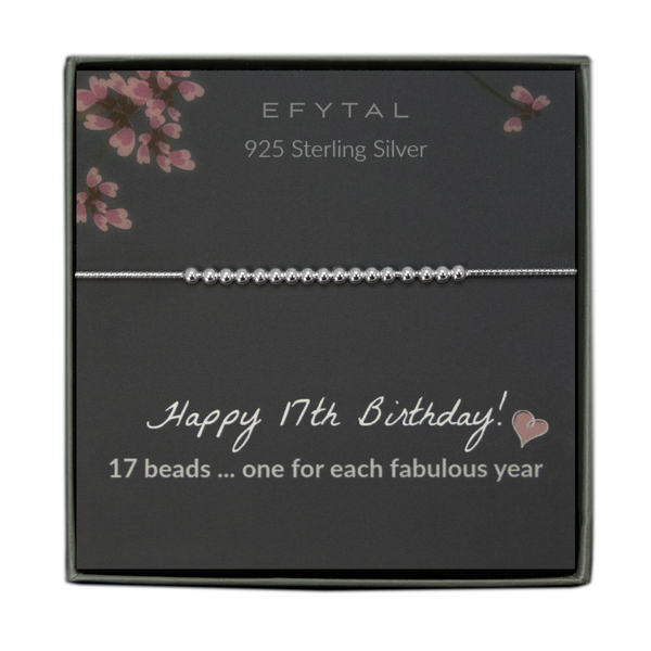  grey jewelry box containing a silver bracelet with seventeen round silver beads, placed on a grey card with pink flowers at the top. the text on the card reads "EFYTAL 925 sterling silver" at the top and "Happy 17th Birthday! <3 17 beads... one for each fabulous year" at the bottom.