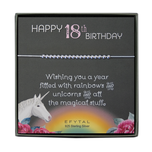 grey jewelry box containing silver bracelet with eighteen round silver beads, placed on a grey card. The bottom left corner of the card has a unicorn and roses, there is a rainbow in the bottom center, and a rose on the bottom right corner. The card reads "Happy 18th birthday" in pink and white font at the top, and "Wishing you a year filled with rainbows and unicorns and all the magical stuff <3" underneath in white. "EFYTAL 925 sterling silver" is in small dark text at the bottom of the card. 
