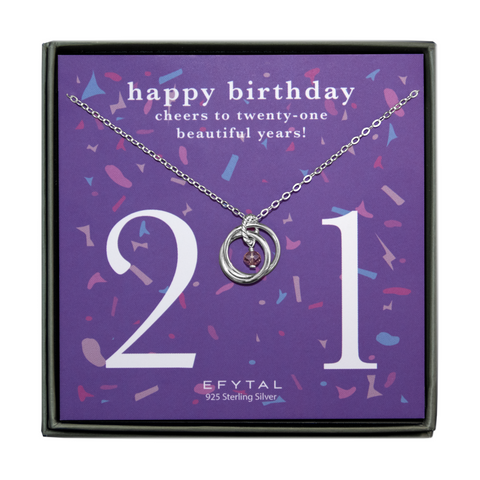 grey jewelry box containing silver necklace with two intertwined rings encircling a dangling purple gem, placed on purple card with confetti print and large number 21 in white font. the card reads "happy birthday. cheers to 21 beautiful years!" in white font at the top, and "EFTYAL 925 Sterling Silver" in small print at the bottom.