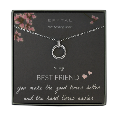A grey jewelry box holds a grey message card with pink flower and branch motif on the top. A sterling silver necklace with two joined rings, one beaded and one plain, rest on the card. The white text at the top of the card reads "EFYTAL 925 Sterling Silver" and the text at the bottom of the card reads "to my BEST FRIEND <3 <3 you make the good times better and the hard times easier." 