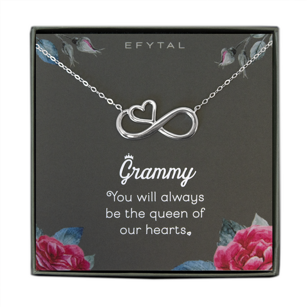 A grey jewelry box containing a grey message card with pink rose motif in the bottom two corners, and rosebuds with leaves in the top two. A sterling silver necklace with a half heart half infinity sign pendant rests on the card. The white text on the card reads "EFYTAL" at the top and “Grammy You will always be the queen of our hearts <3” at the bottom.