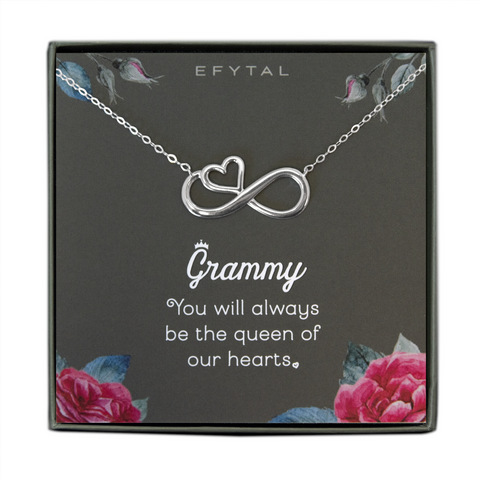 A grey jewelry box containing a grey message card with pink rose motif in the bottom two corners, and rosebuds with leaves in the top two. A sterling silver necklace with a half heart half infinity sign pendant rests on the card. The white text on the card reads "EFYTAL" at the top and “Grammy You will always be the queen of our hearts <3” at the bottom.