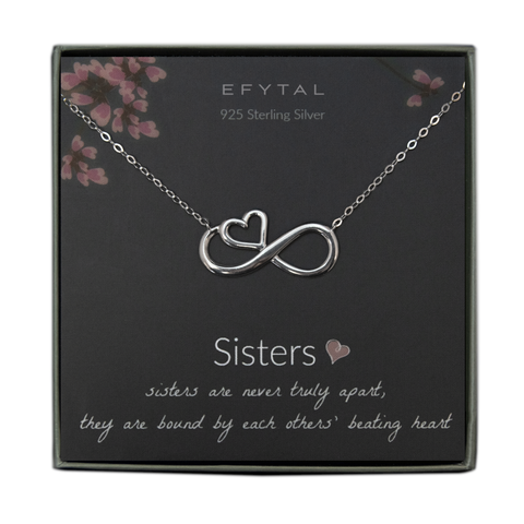 A grey jewelry box containing a grey message card with pink floral motif at the top. A silver necklace with an infinity sign pendant with an embedded heart on it rests on the card. The white text on the card reads "EFYTAL 925 Sterling Silver" at the top and “Sisters <3 sisters are never truly apart, they are bound by each others' beating heart" at the bottom